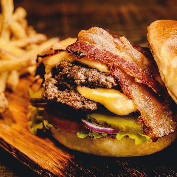 A double bacon cheeseburger with lettuce, tomato, onion, and pickles, served with fries.