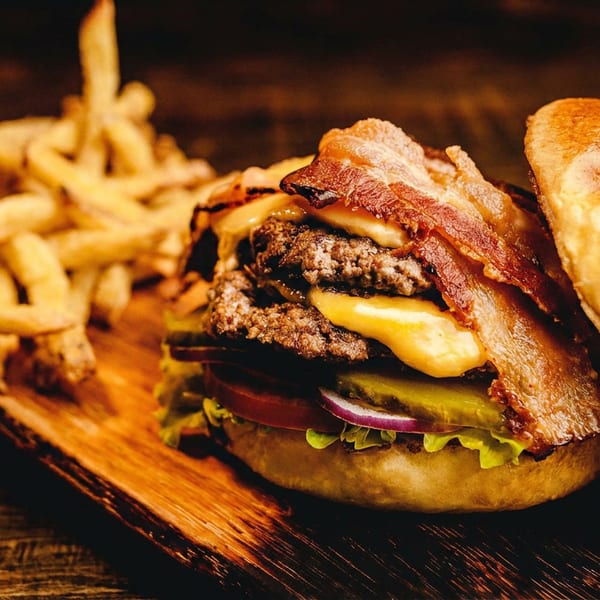 Double bacon cheeseburger with lettuce, tomato, onion, pickles, and a side of fries.